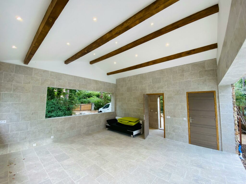 pexels photo 14183828 14183828 Spacious modern room with natural light, wooden beams, and stone walls.